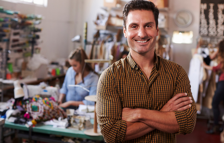 Male entrepreneur in clothing design studio, arms crossed